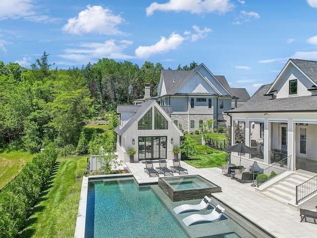 rear view of property with a swimming pool with hot tub, a sunroom, and a patio