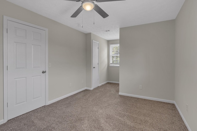 unfurnished room with light carpet, ceiling fan, and a textured ceiling