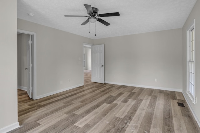 spare room with ceiling fan, light hardwood / wood-style floors, and a textured ceiling