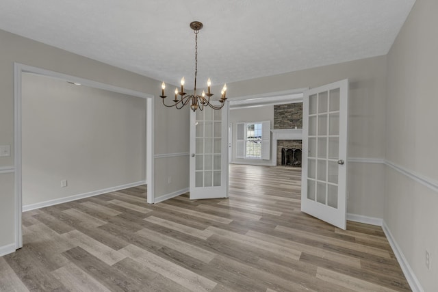 unfurnished dining area with a chandelier, light hardwood / wood-style flooring, and french doors