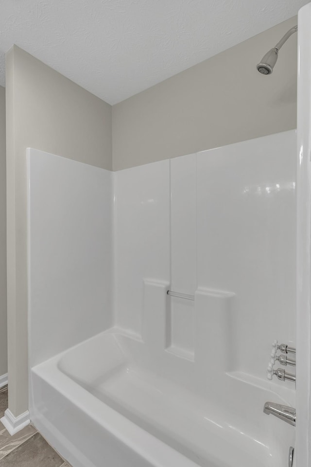 bathroom with tub / shower combination and a textured ceiling