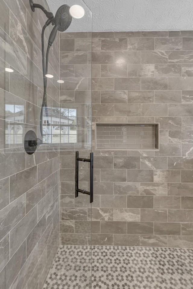 bathroom featuring a textured ceiling and a shower with door