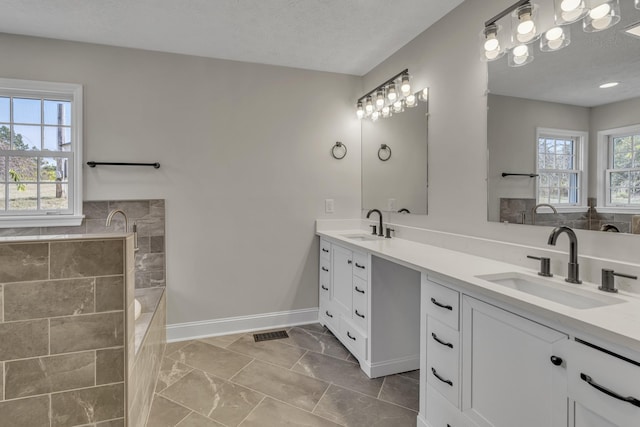 bathroom with a washtub, a textured ceiling, and vanity