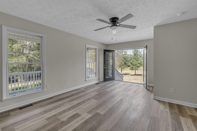 spare room featuring a textured ceiling, ceiling fan, and light hardwood / wood-style floors