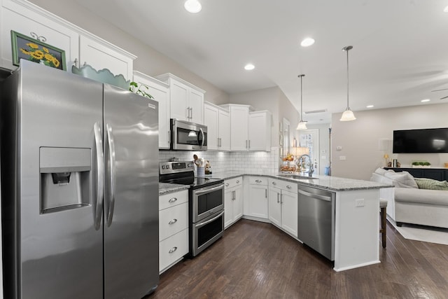 kitchen featuring pendant lighting, appliances with stainless steel finishes, white cabinetry, sink, and kitchen peninsula