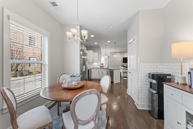 dining room with dark hardwood / wood-style floors, sink, and an inviting chandelier