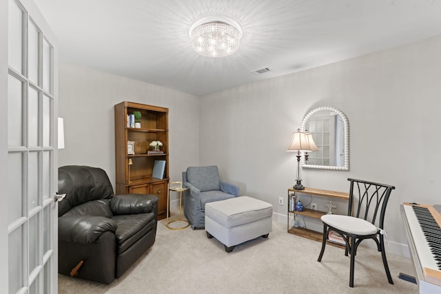 living area with light colored carpet and a notable chandelier