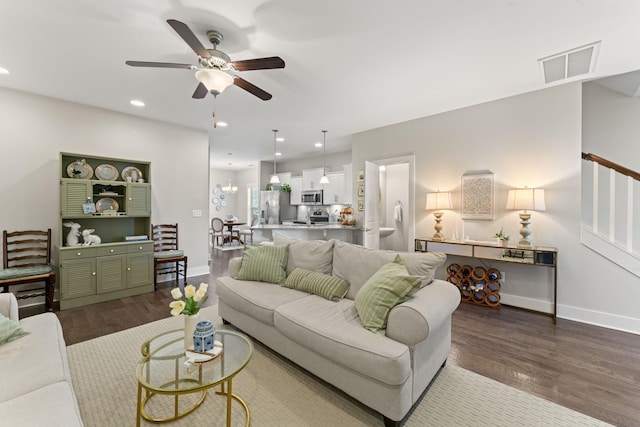 living room featuring ceiling fan with notable chandelier and hardwood / wood-style flooring