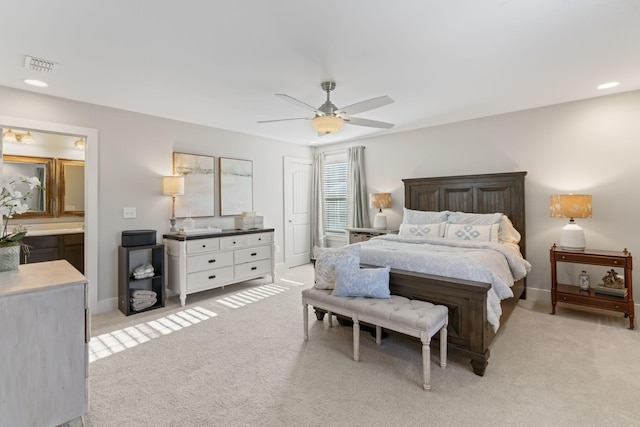 bedroom with ceiling fan, connected bathroom, and light carpet