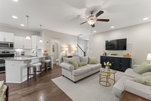 living room with ceiling fan, sink, and dark hardwood / wood-style flooring