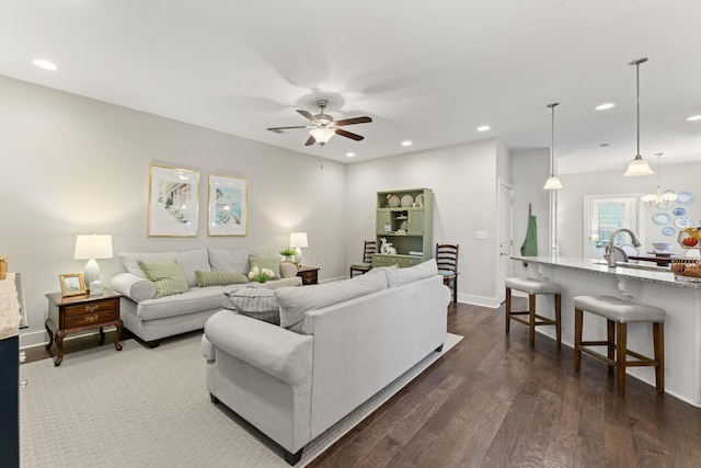 living room featuring ceiling fan with notable chandelier and dark hardwood / wood-style floors