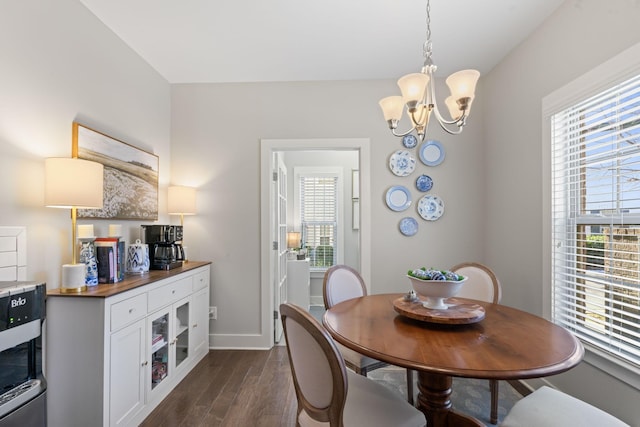 dining area with dark hardwood / wood-style flooring and an inviting chandelier