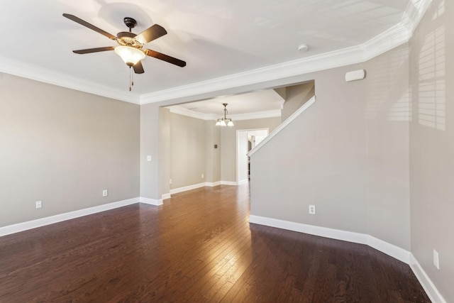 empty room with dark wood-type flooring, crown molding, and ceiling fan with notable chandelier