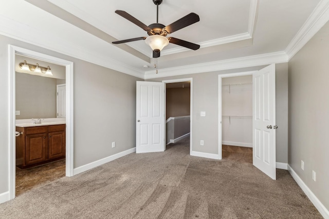 unfurnished bedroom with ceiling fan, crown molding, a raised ceiling, and ensuite bath