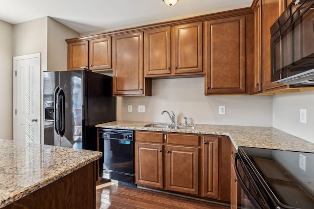 kitchen with light stone countertops, sink, dark hardwood / wood-style floors, and black appliances