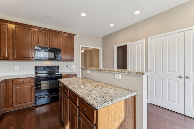 kitchen featuring black appliances, dark wood-type flooring, light stone counters, and a center island