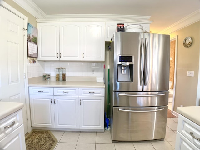 kitchen with white cabinetry, backsplash, stainless steel fridge, ornamental molding, and light tile patterned floors