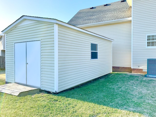 view of outdoor structure with a lawn and central AC