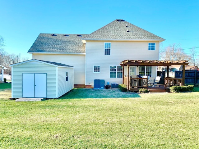 rear view of property featuring a pergola, a wooden deck, a shed, and a lawn