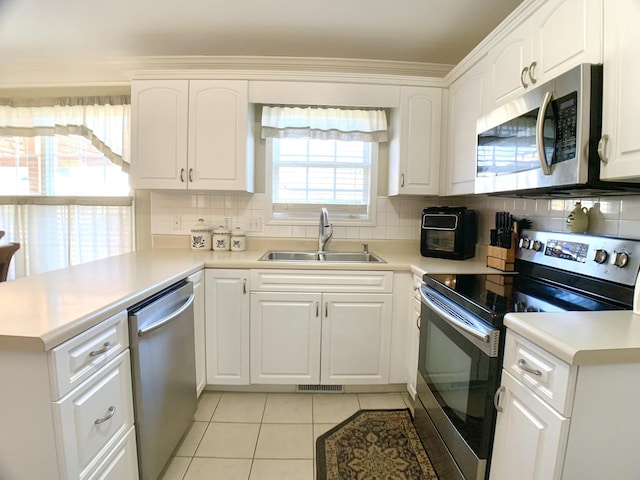 kitchen with light tile patterned floors, appliances with stainless steel finishes, sink, and white cabinetry