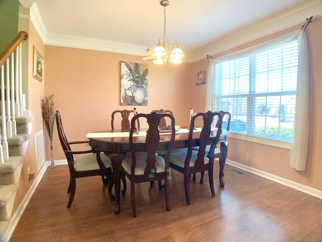 dining room featuring dark wood-type flooring, crown molding, and a notable chandelier