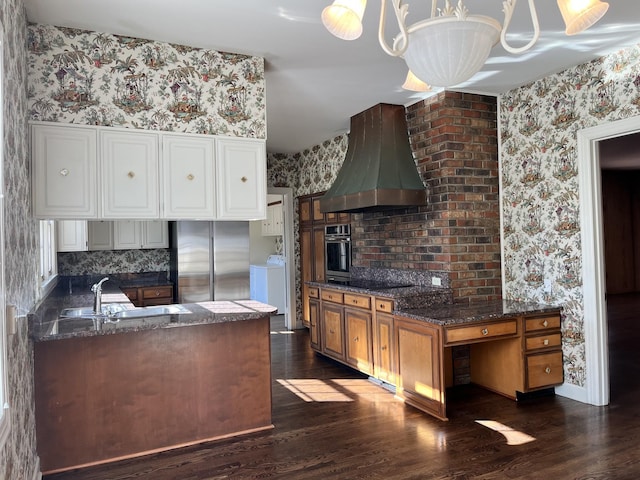 kitchen featuring pendant lighting, appliances with stainless steel finishes, wall chimney range hood, dark hardwood / wood-style flooring, and a chandelier