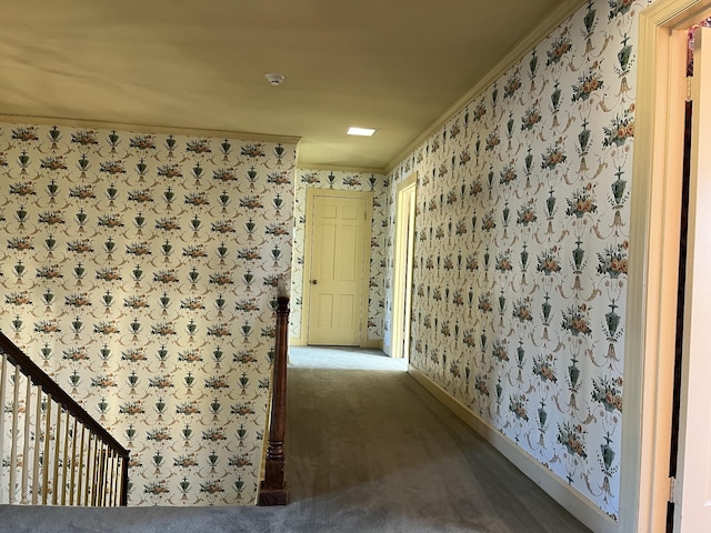 hall with dark colored carpet and ornamental molding