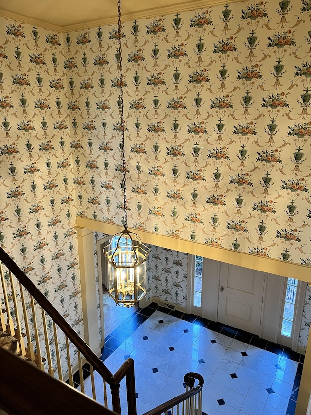 interior space with dark tile patterned floors, crown molding, and a chandelier