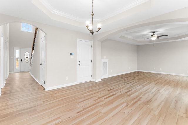 unfurnished room featuring plenty of natural light, ceiling fan with notable chandelier, and a tray ceiling