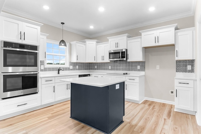 kitchen featuring a center island, decorative light fixtures, white cabinetry, stainless steel appliances, and crown molding