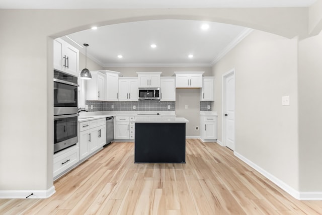 kitchen with backsplash, a kitchen island, hanging light fixtures, appliances with stainless steel finishes, and white cabinets