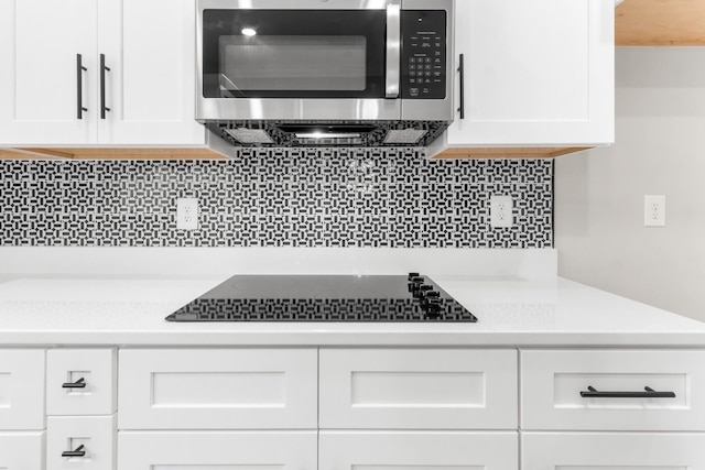 kitchen featuring black electric stovetop, white cabinets, and tasteful backsplash