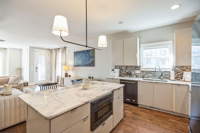 kitchen with pendant lighting, dishwasher, a center island, sink, and stainless steel microwave