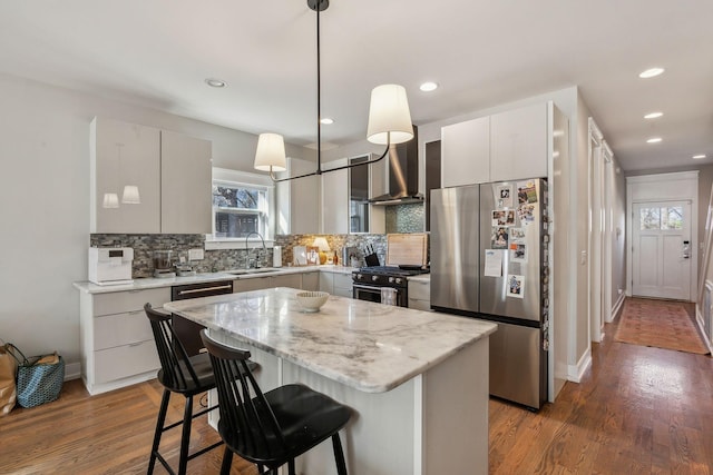 kitchen with wall chimney range hood, a center island, high end black range oven, hanging light fixtures, and stainless steel fridge