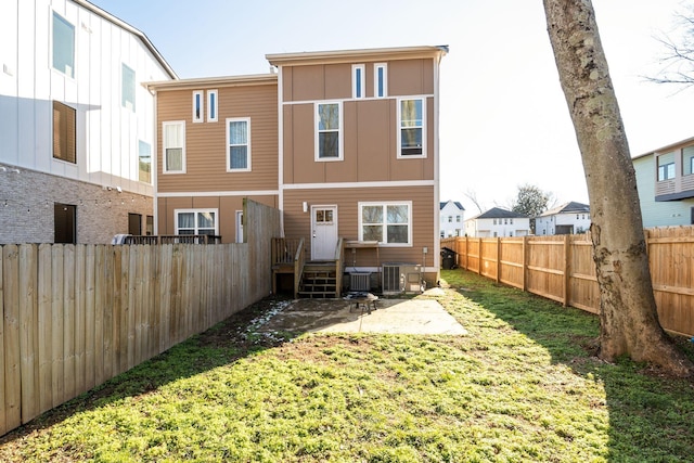 rear view of house with central AC unit and a yard