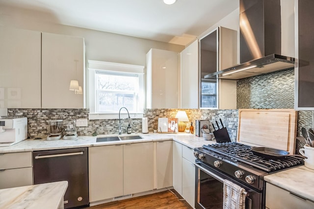 kitchen with backsplash, wall chimney range hood, sink, appliances with stainless steel finishes, and light stone counters