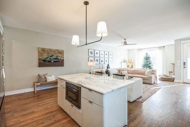 kitchen featuring white cabinetry, ceiling fan, decorative light fixtures, built in microwave, and a kitchen island