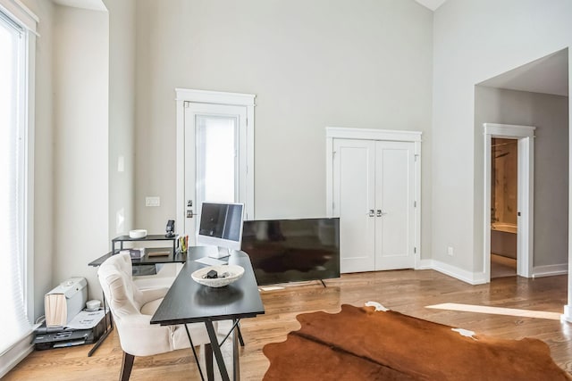 office with a high ceiling and hardwood / wood-style floors