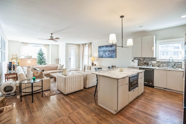 kitchen featuring white cabinetry, appliances with stainless steel finishes, a center island, decorative light fixtures, and sink