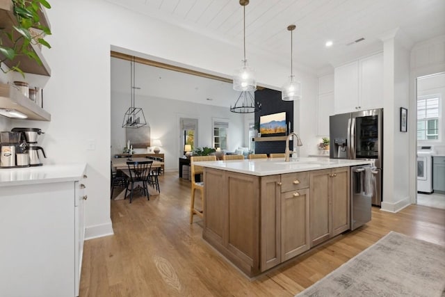 kitchen with a center island with sink, pendant lighting, stainless steel dishwasher, white cabinets, and sink