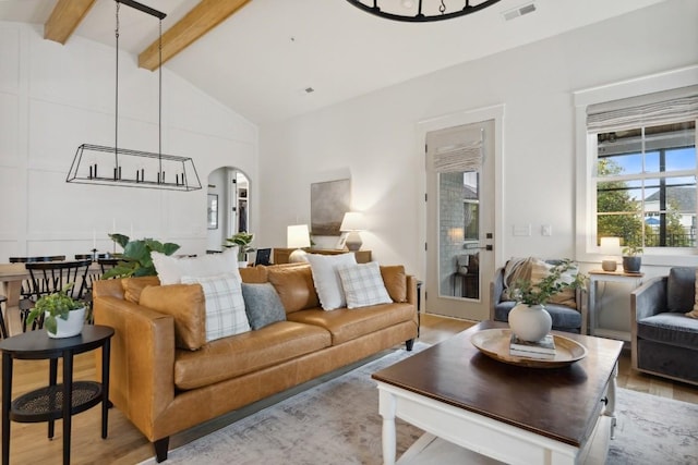 living room featuring lofted ceiling with beams and light hardwood / wood-style flooring