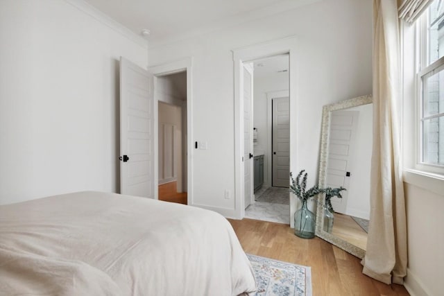 bedroom featuring ensuite bath, crown molding, hardwood / wood-style flooring, and multiple windows