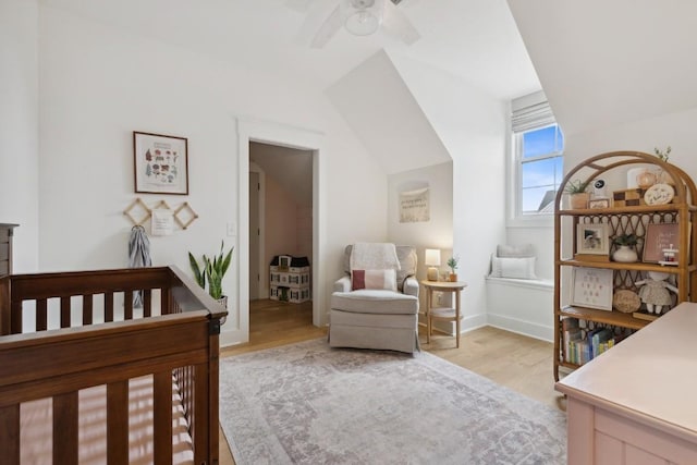 bedroom featuring ceiling fan, light hardwood / wood-style floors, and a crib