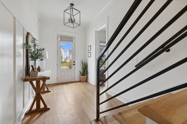 entrance foyer featuring crown molding, an inviting chandelier, and light hardwood / wood-style floors