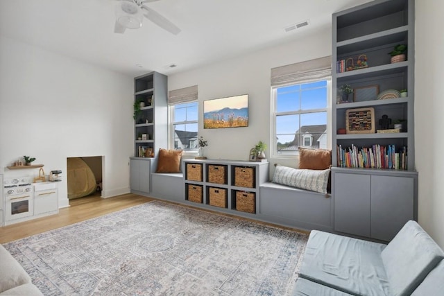 living area featuring ceiling fan, a wealth of natural light, and light hardwood / wood-style floors