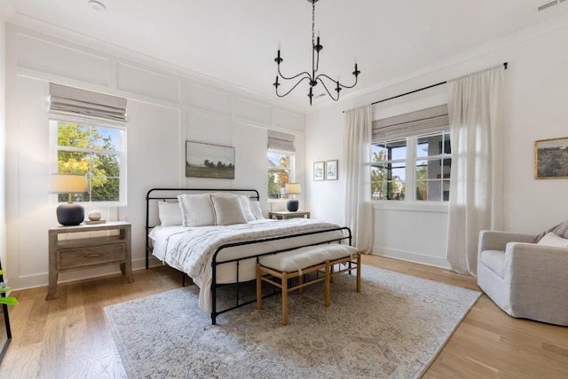 bedroom with a notable chandelier, crown molding, wood-type flooring, and multiple windows