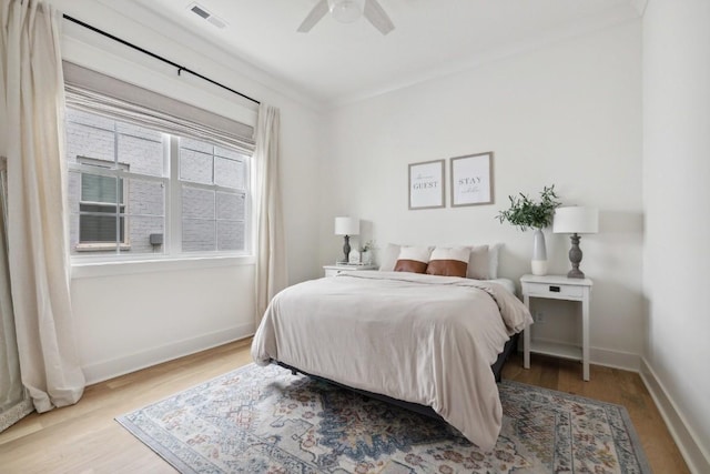 bedroom with ceiling fan, ornamental molding, and light hardwood / wood-style floors