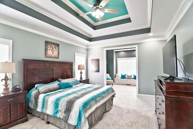 carpeted bedroom with ceiling fan, crown molding, and a tray ceiling