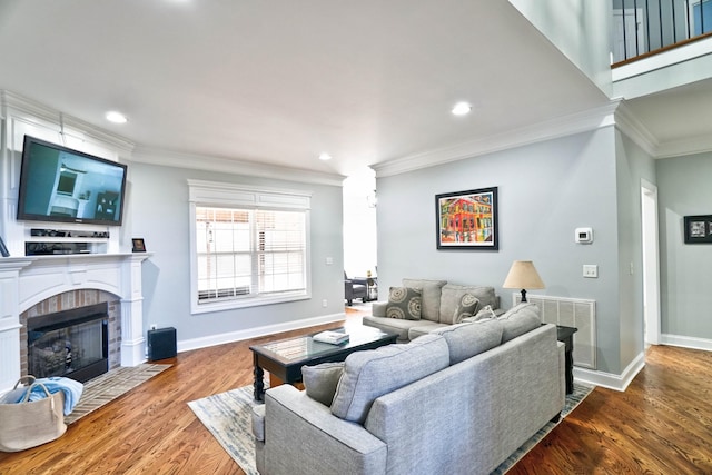 living room featuring hardwood / wood-style flooring, a tile fireplace, and ornamental molding