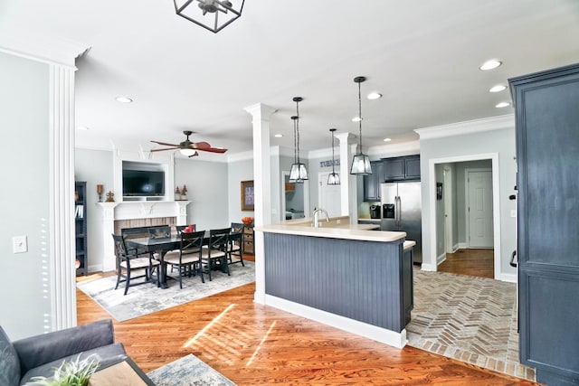 kitchen with pendant lighting, stainless steel fridge with ice dispenser, ornamental molding, ceiling fan, and light hardwood / wood-style flooring